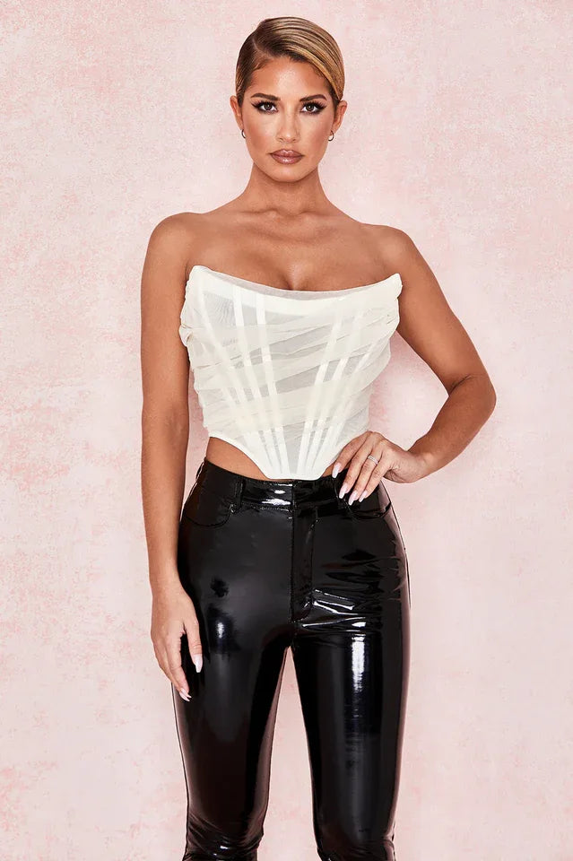woman wearing a white strapless corset top and black pants, front view