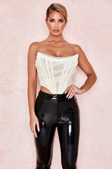 woman wearing a white strapless corset top and black pants, front view