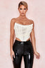 woman wearing a white strapless corset top and black pants, close-up
