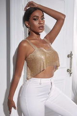Woman posing with her arm raised, wearing a gold rhinestone crop top and white pants