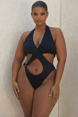 Plus-size woman in black one-piece swimsuit with halter neckline and cut-out details.