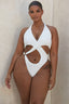 Plus-size woman in white one-piece swimsuit with halter neckline and cut-out details.