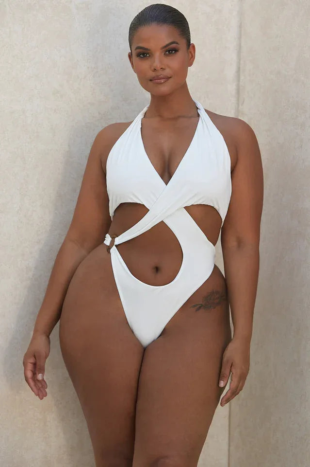 Plus-size woman in white one-piece swimsuit with halter neckline and cut-out details.