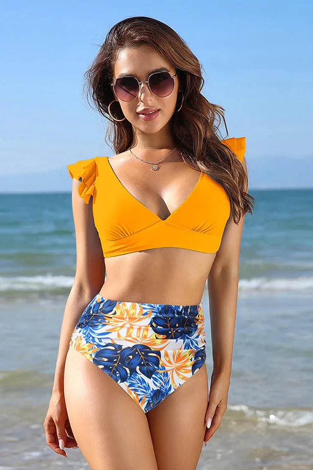 Woman wearing an orange bikini with floral high-waisted bottoms on the beach, front view