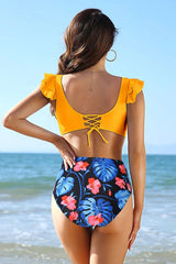 Woman wearing a yellow bikini with floral high-waisted bottoms on the beach, back view