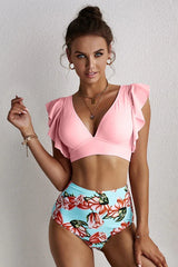 Woman wearing a pink v-neck bikini top with flutter sleeves and floral high-waisted bottoms