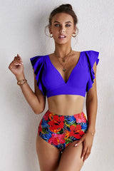 Woman wearing a royal blue v-neck bikini top with flutter sleeves and colorful floral high-waisted bottoms