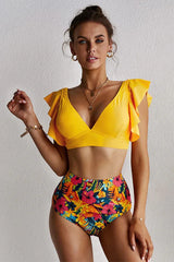 Woman wearing a yellow v-neck bikini top with flutter sleeves and tropical floral high-waisted bottoms