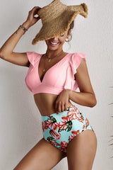 Woman wearing a pink bikini top with flutter sleeves and floral high-waisted bottoms, holding a straw hat