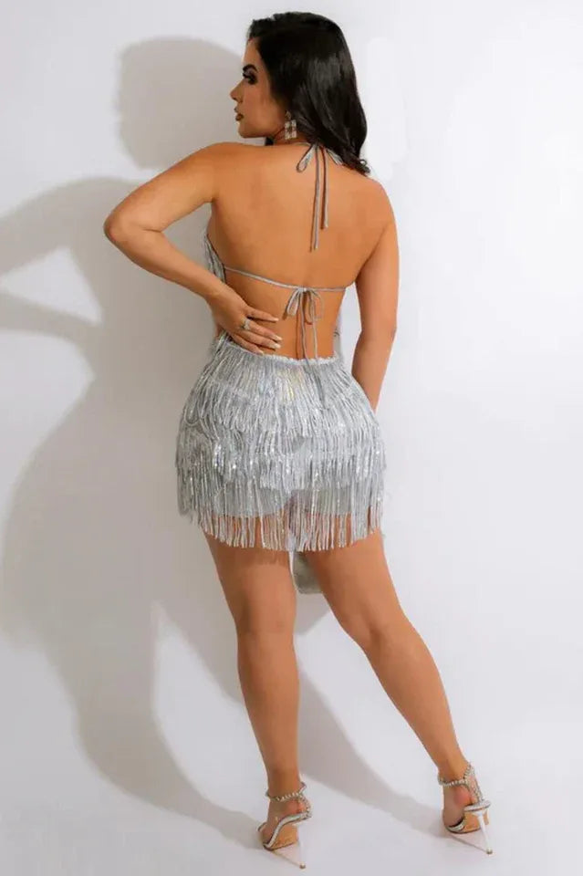 Woman in a silver sequined fringe mini dress, full body back view