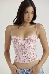 Close-up of a woman wearing a pink lace corset top with delicate spaghetti straps.