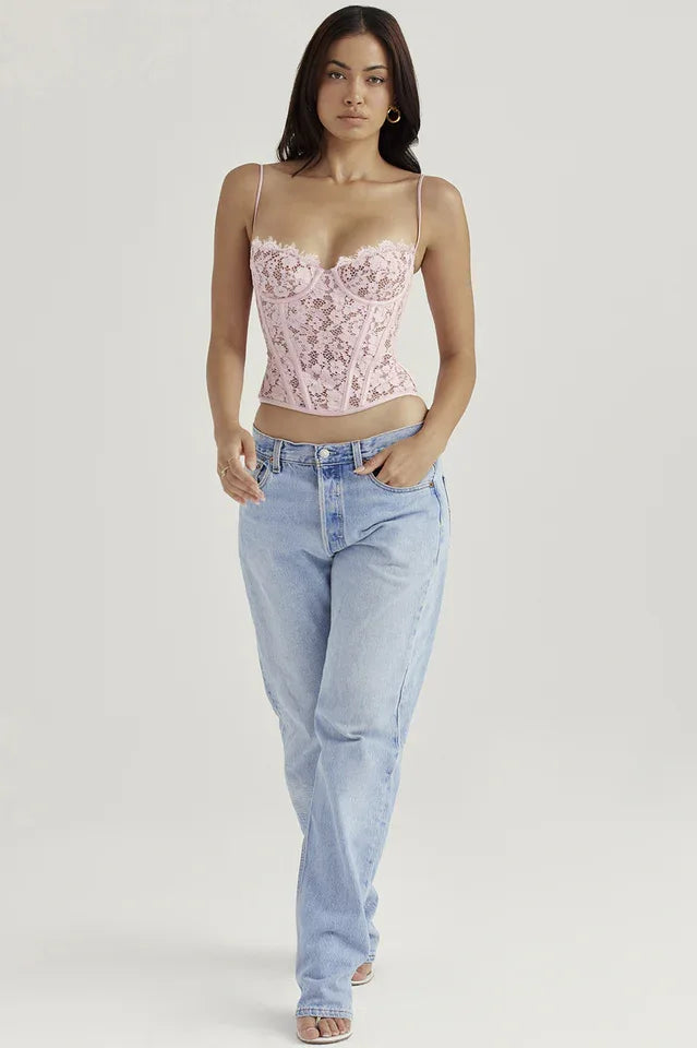 Woman wearing a pink lace corset top and light wash denim jeans, facing forward.