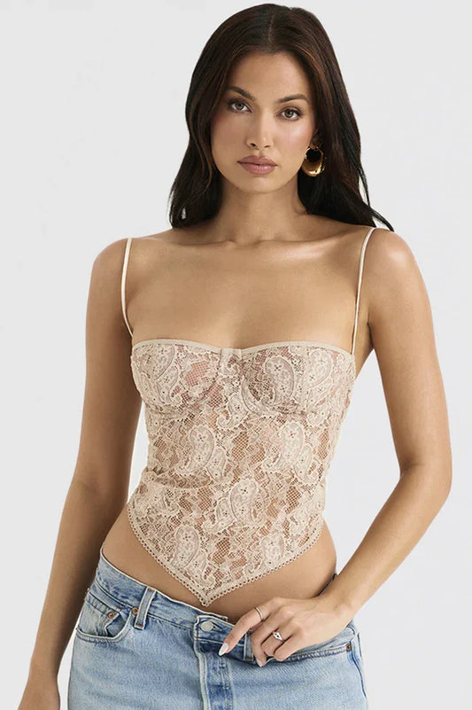 Woman wearing a beige lace corset top with a scarf hem and spaghetti straps, paired with light-wash denim jeans.