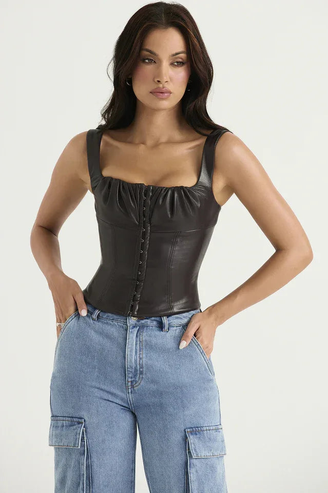 Front view of a woman wearing a dark brown faux leather corset top with a square neckline and hook and eye front closure, paired with light wash denim cargo pants.
