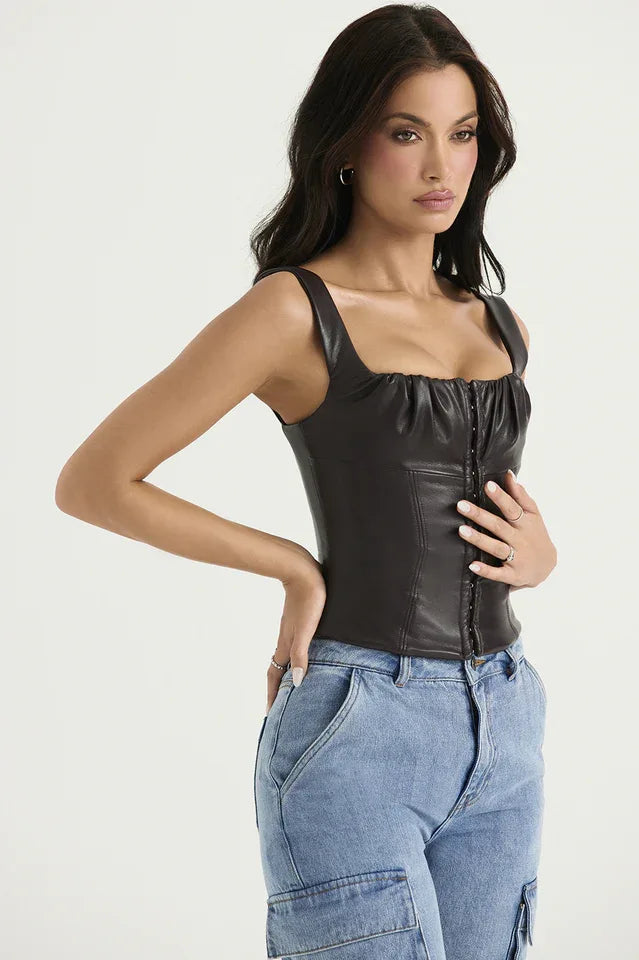 Side view of a woman wearing a dark brown faux leather corset top with a square neckline and hook and eye front closure, paired with light wash denim cargo pants.
