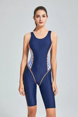 Woman in a navy blue one-piece swimsuit with geometric side panels, standing and facing forward