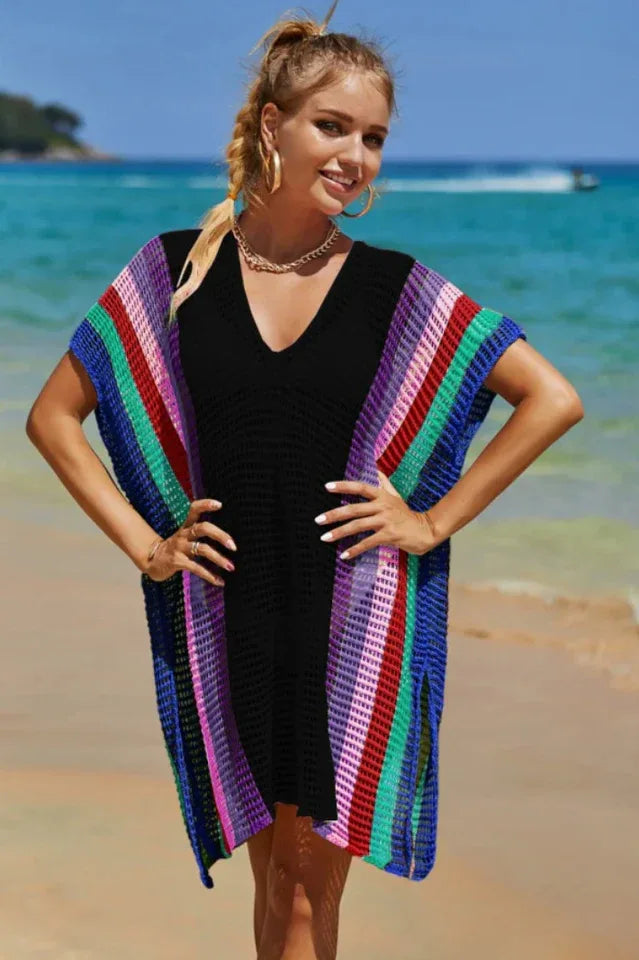 Woman wearing a black beach cover-up with colorful striped accents on the beach.