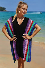 Woman wearing a black beach cover-up with colorful striped accents on the beach.