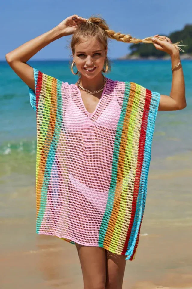 Woman wearing a pink and rainbow striped knit beach cover-up on the beach.