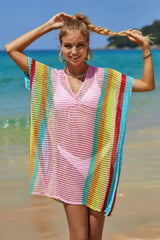 Woman wearing a pink and rainbow striped knit beach cover-up on the beach.