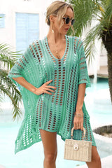 Woman wearing a green crocheted knit poncho cover-up with a v-neck, short sleeves, and sunglasses.