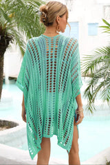 Back view of a woman wearing a green crocheted knit poncho cover-up with a v-neck and short sleeves.