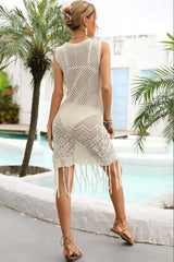 Back view of a woman in a cream crochet knit sleeveless dress with fringe hem