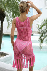 Back view of a woman wearing a pink crochet knit beach cover-up with tassel hem