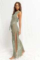 Woman wearing a green crochet knit maxi dress with a high slit, side view.