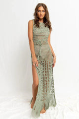 Woman wearing a green crochet knit maxi dress with a high slit and fringe hem, front view.