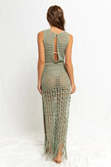Woman wearing a green crochet knit maxi dress with a high slit and fringe hem, back view.