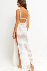 Woman wearing a white crocheted maxi dress with a high slit and fringe hem, viewed from the back.