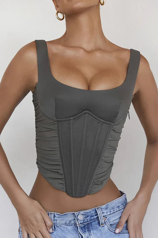 Woman wearing a khaki ruched corset top with a square neckline and denim jeans.