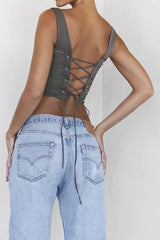 Back view of a woman wearing a khaki ruched corset top with a lace-up back detail and denim jeans.