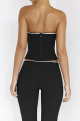 Back view of a woman wearing a black strapless corset top with a zipper closure and matching black high-waisted pants with crystal trim.