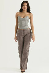 Full body shot of a model in a gray strapless lace-up corset top and brown faux leather lace-up pants