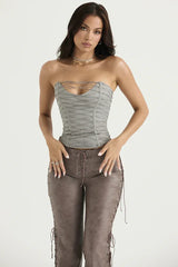 Front view of a model wearing a gray strapless lace-up corset top and brown faux leather lace-up pants