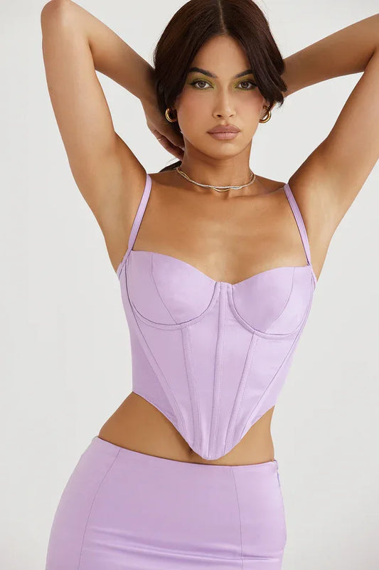 Model wearing a lavender corset top with hands behind head