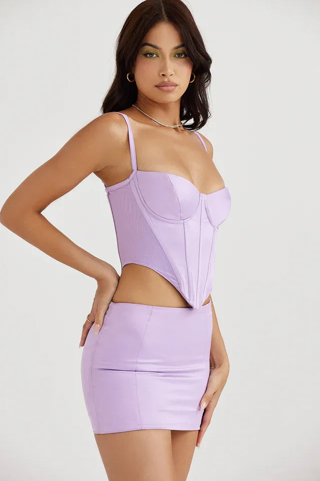 Model wearing a lavender corset top and skirt, hands on hips