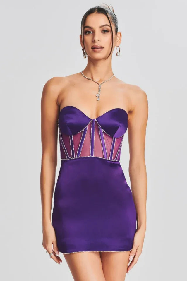 Model wearing a strapless purple satin mini dress with sheer corset-inspired panels and crystal embellishments.