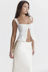 Side profile of a woman wearing a white embroidered eyelet sleeveless square neck top with a tie front.