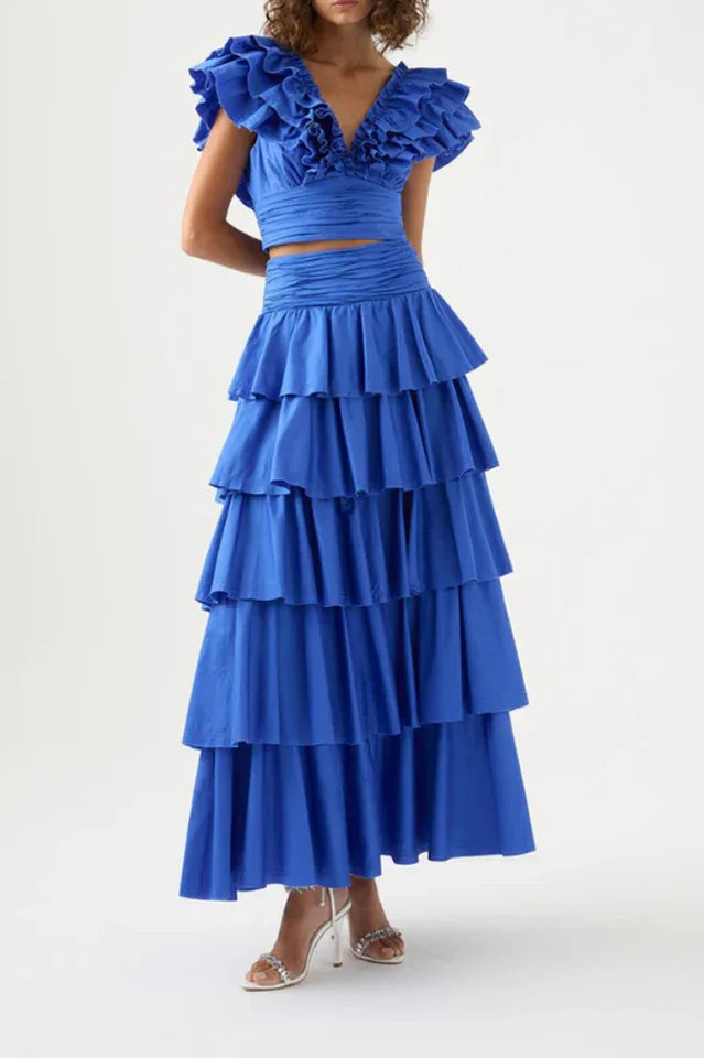 Front view of a woman in a blue ruffled crop top and tiered blue maxi skirt