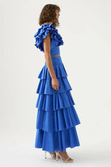 Side view of a woman in a blue ruffled crop top and tiered blue maxi skirt
