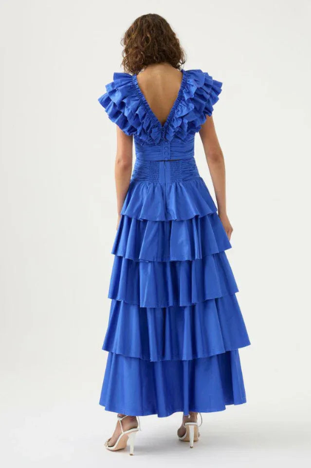 Back view of a woman in a blue ruffled crop top and tiered blue maxi skirt