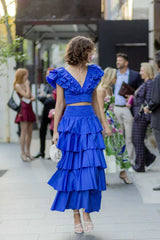Woman wearing a blue ruffled crop top and tiered blue maxi skirt walking outdoors