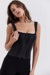 Woman wearing a black corset top with a sweetheart neckline and tie detail, showing shoulder strap detail
