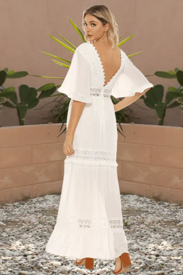 Back view of a woman wearing a white lace-trimmed maxi dress with a deep V-back.