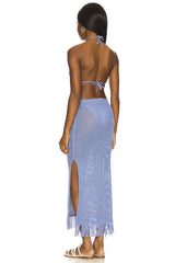 Back view of a woman in a blue crochet knit maxi dress with a halter neck and high slit.