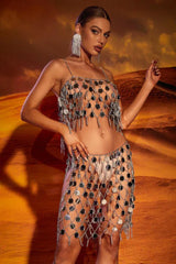 Woman posing in a shimmering silver sequin festival outfit with long statement earrings