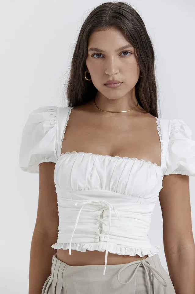 Close-up of a white cropped puff sleeve top with a ruched bodice and tie front.